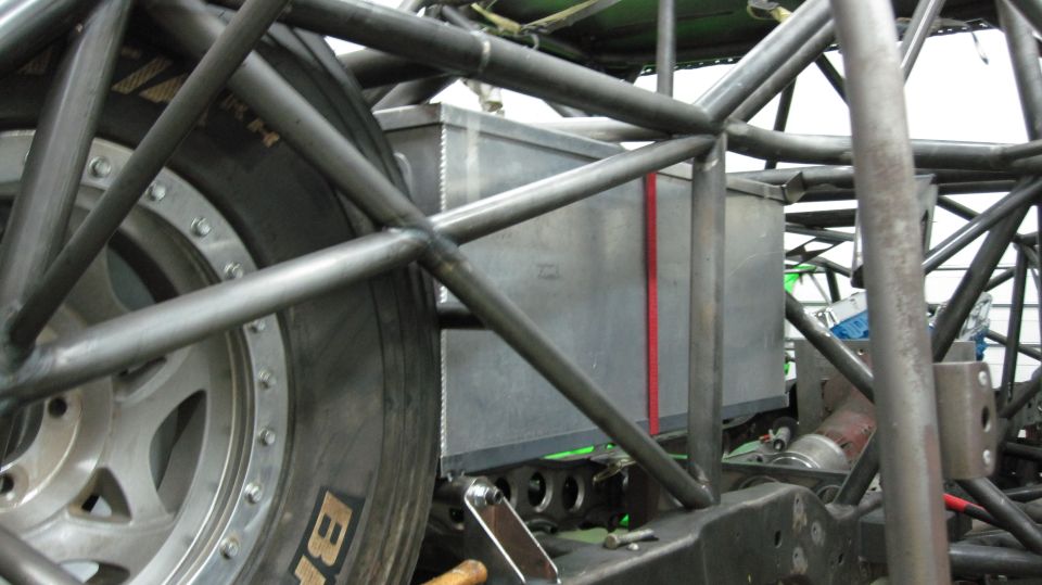 Close-up of a custom roll cage with a fuel cell and tire visible