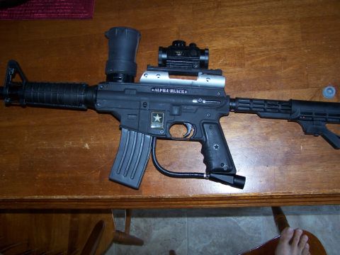 1986 Ford Bronco - A paintball marker with an optic sight and hopper is displayed on a wooden surface.