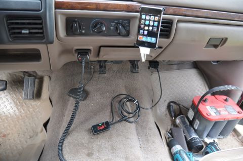 1996 Ford Bronco - The interior of a vehicle shows an iPhone mounted on the dash, along with pedals and a battery in the footwell. A PLX device is also visibl…