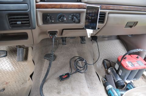 1996 Ford Bronco - The interior of a vehicle is cluttered with accessories and tools, including a phone mount and a diagnostic device plugged into the dash.