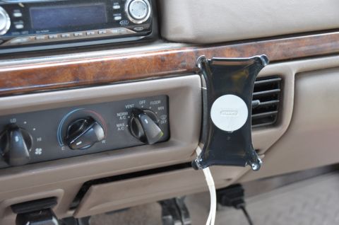 1996 Ford Bronco - Close-up of a car's interior dashboard, showing climate controls and a phone holder attached to the dash.