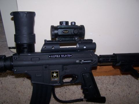 1986 Ford Bronco - A black paintball gun with "ALPHA BLACK" branding and a U.S. Army insignia is shown with its attached optics.