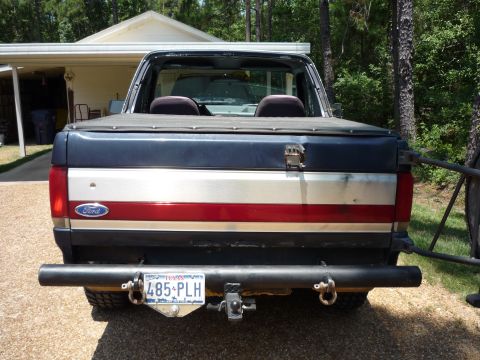 1990 Ford Bronco - This Ford pickup truck features a distinctive red, white, and blue stripe on its tailgate.