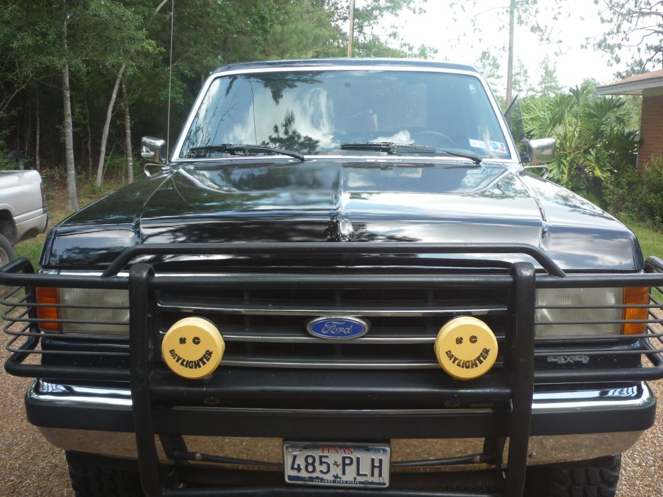 Black 1990 Ford Bronco front view with brush guard and yellow fog lights