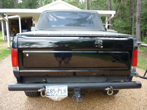 1990 Ford Bronco - Rear view of a black 1990 Ford Bronco, showing its soft top and custom bumper.