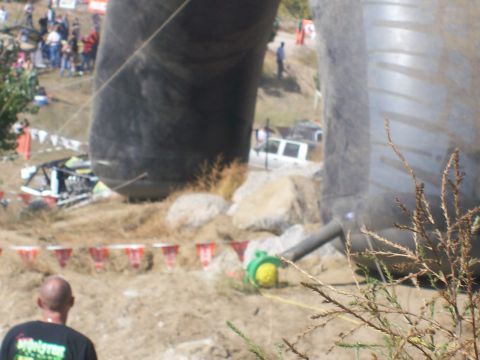 1993 Ford Bronco - A white SUV is visible on a dirt track, with a damaged vehicle and large inflatable structures in the background.