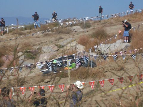 1993 Ford Bronco - A blurry off-road vehicle navigates a challenging course, observed by spectators lining the track.