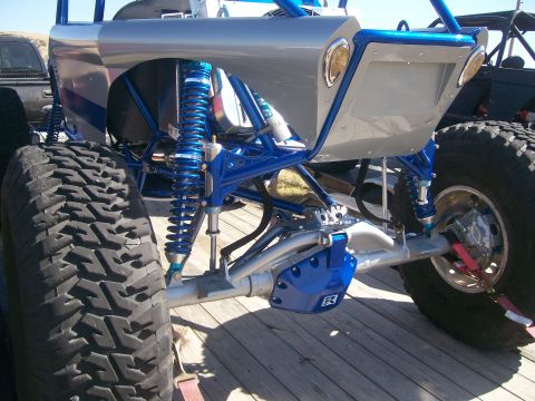 1993 Ford Bronco - This custom buggy features a heavily modified suspension system with bright blue coilover shocks and a silver body.