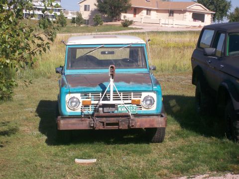 1972 Ford Bronco - A blue and white 1972 Ford Bronco sits in a grassy yard next to another dark-colored vehicle.
