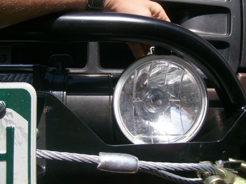 1993 Ford Bronco - Close-up of an off-road vehicle's front bumper, a winch and a round auxiliary light.