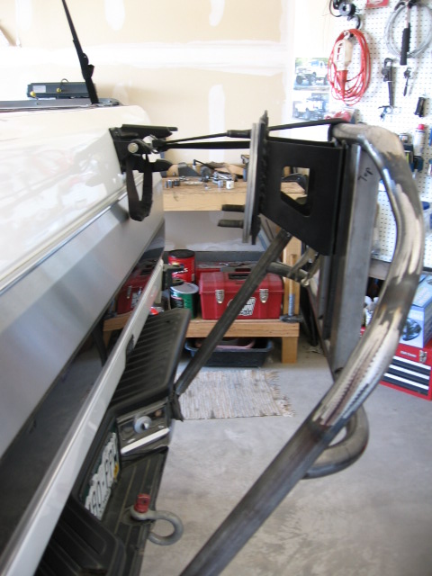1995 Ford Bronco - A custom tire carrier mount is attached to the rear of a white truck, with tools and equipment visible in the background.