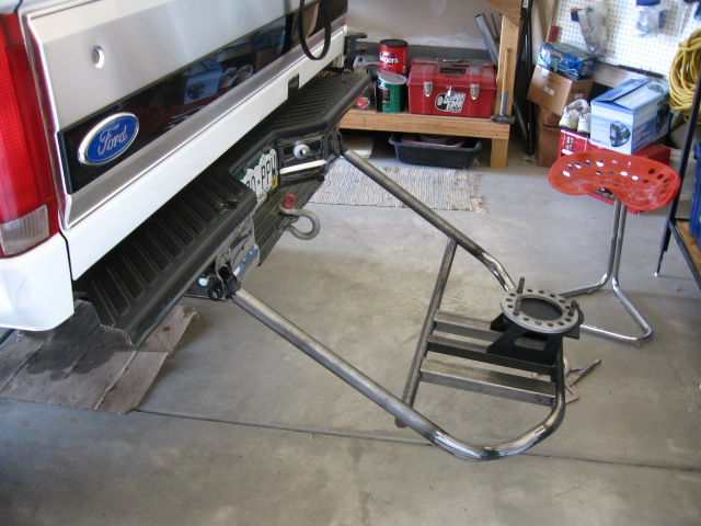 White Ford SUV rear bumper with hitch and a tubular steel fabrication jig on garage floor