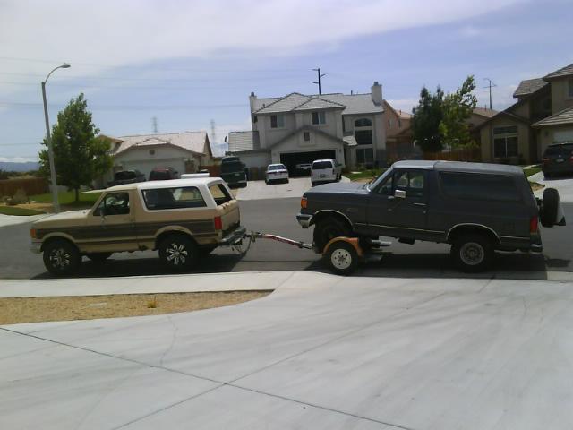 1990 Ford Bronco towing another Bronco, side view