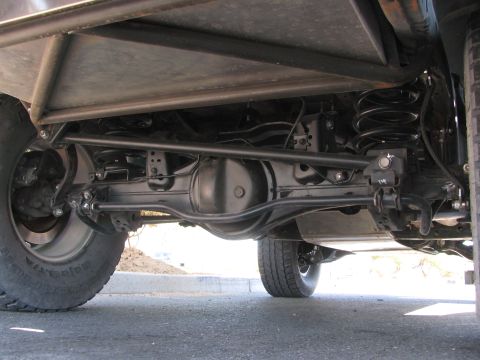 1990 Ford Bronco - Underbody view of a lifted vehicle revealing the rear axle, coil springs, shocks and skid plate.