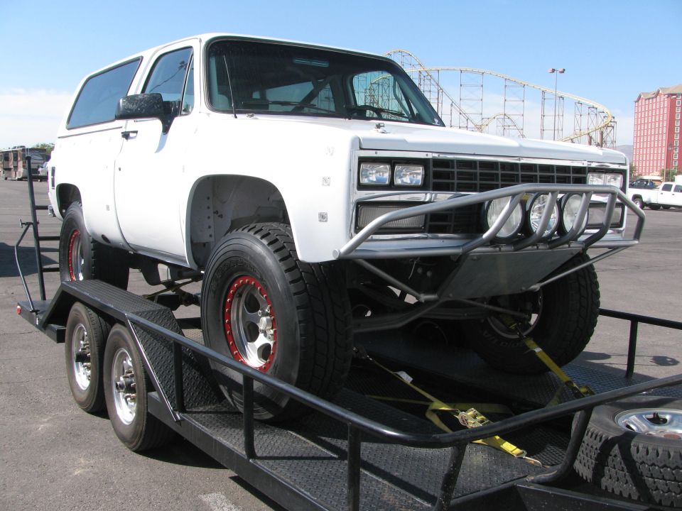 White lifted Chevrolet Blazer with off-road bumper on a trailer outdoors