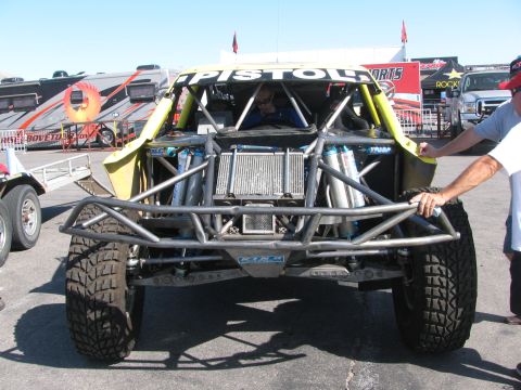 1990 Ford Bronco - Front view of a yellow tube-chassis off-road race truck showing exposed roll cage, radiator and long-travel suspension.