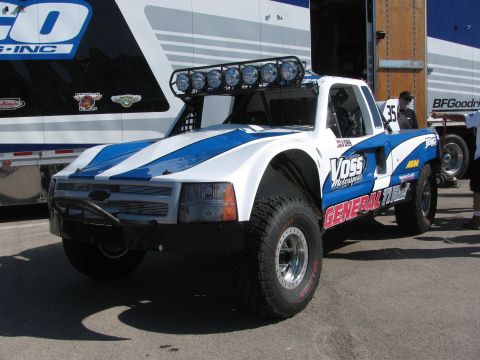 1990 Ford Bronco - blue-and-white off-road race truck numbered 35 with roof light bar and General Tire graphics in a pit area.