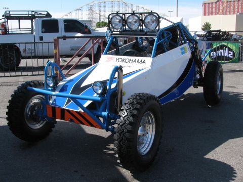 1990 Ford Bronco - white-and-blue open-frame off-road sand rail buggy with overhead lights and Yokohama graphics parked at an event.