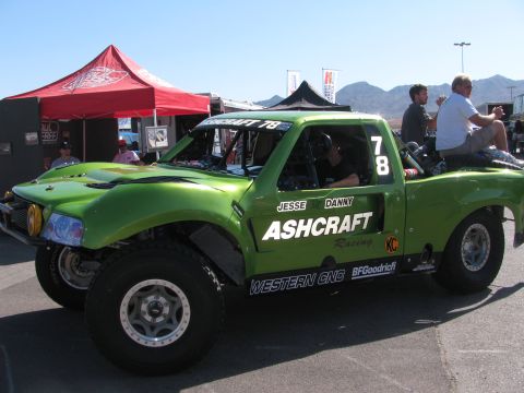 1990 Ford Bronco - lime-green Ford Ranger-based off-road race truck numbered 78 with Ashcraft Racing graphics sits in a sunny desert event pit area.