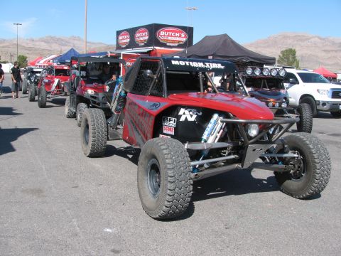 1990 Ford Bronco - red open tube-frame off-road race buggy with K&N and BFGoodrich decals parked in front of a Butch's racing canopy.
