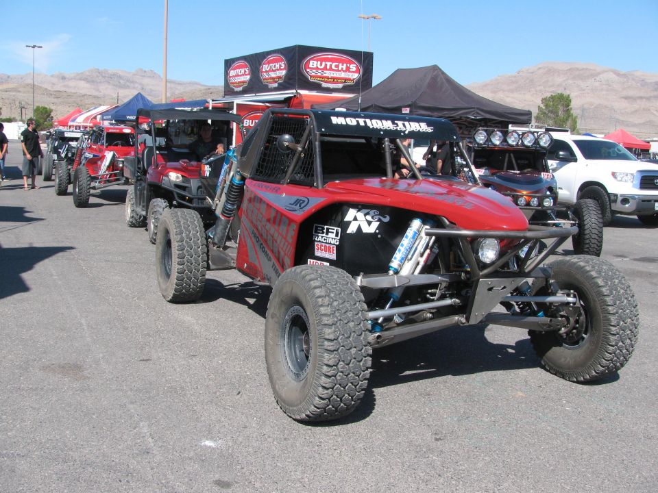 Red tube-frame off-road buggy with K&N decals at Butch's pit canopy