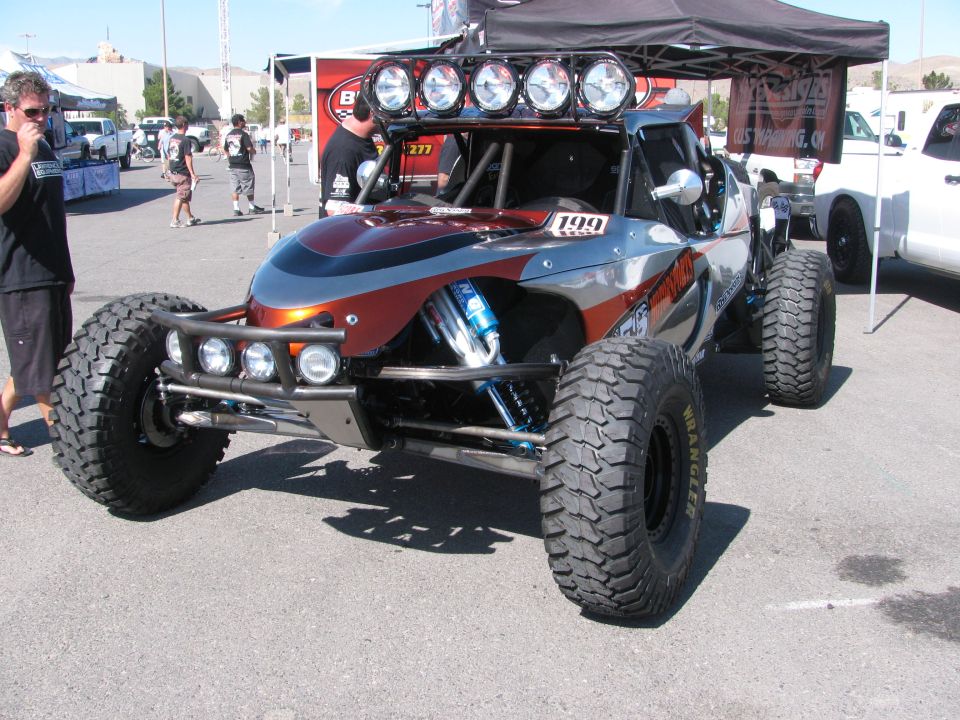Gray and orange tube-frame off-road buggy #199 with overhead lights in pit