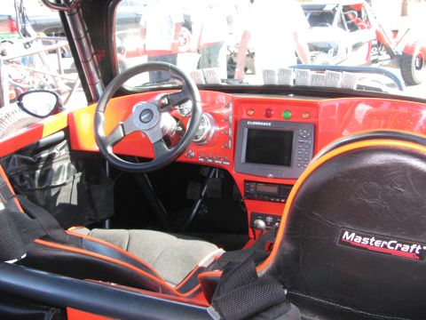 1990 Ford Bronco - cockpit of an off-road race vehicle showing a steering wheel, red dash with a Lowrance screen, and a black MasterCraft seat.
