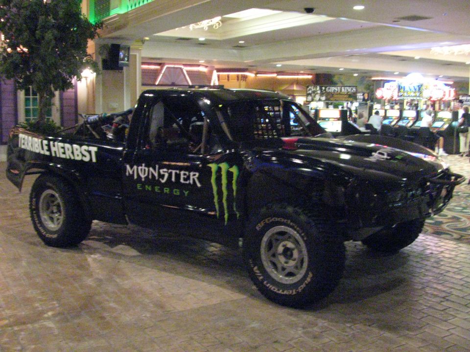 Black Terrible Herbst Monster Energy trophy truck displayed indoors near arcade machines