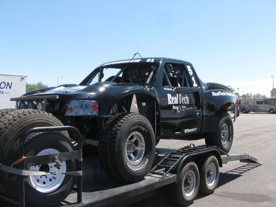 Black RealTech Realty number 51 race truck loaded on a flatbed trailer