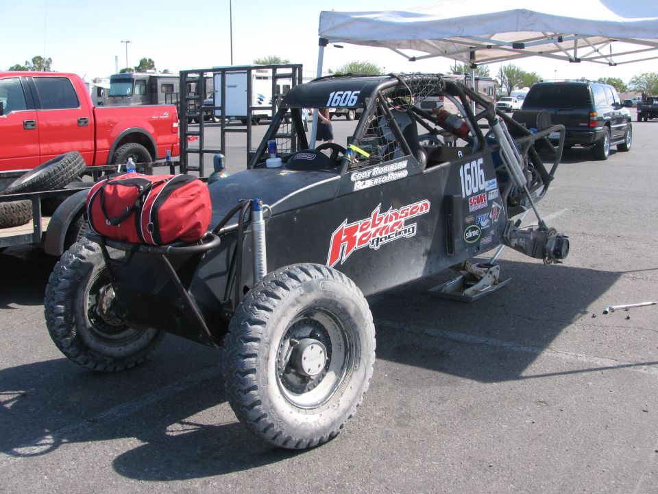 Black Robinson Racing number 1606 off-road buggy with red gear bag in a paddock