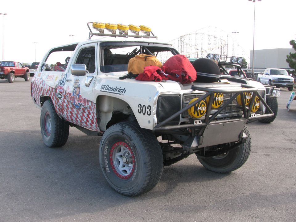 Front three-quarter view of #303 race truck with roof light bar near amusement park rides