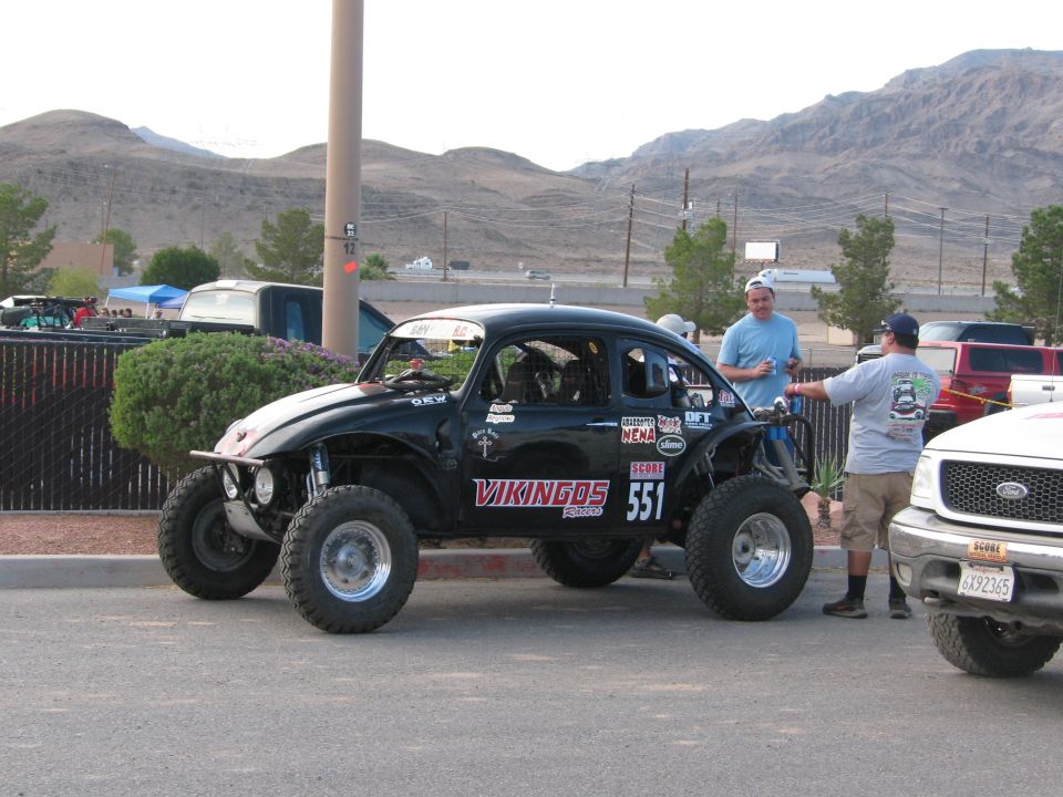 Black Baja Bug race car #551 Vikingos with two men standing beside it