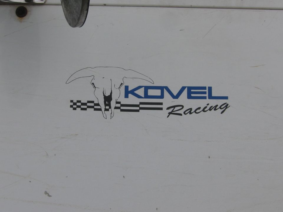 Close-up of Kovel Racing longhorn-skull logo on a white panel