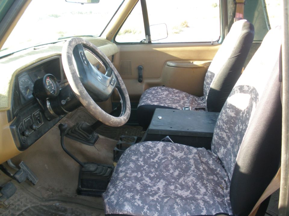 Interior view of a vehicle with camouflage seat covers and a aftermarket gauge