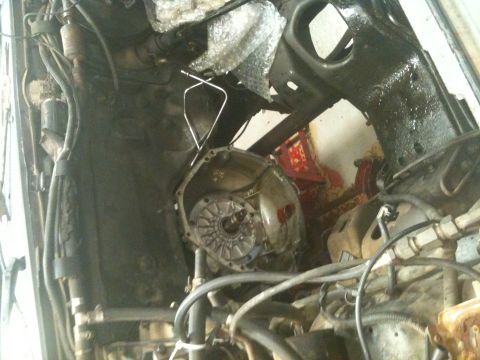1990 Ford C-150 (Centurion Conversions) - Close-up view of the transmission housing and surrounding engine components, with visible wiring and metal framing.