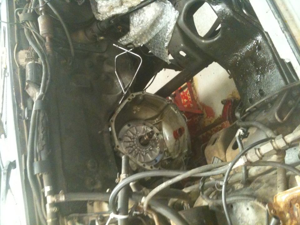 Underside view of vehicle transmission and engine bay, showing mechanical parts and wiring