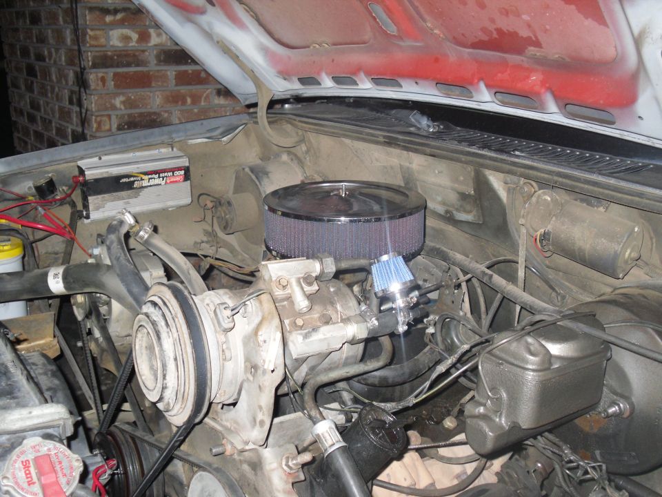 Engine bay with air filter, battery, and AC compressor visible