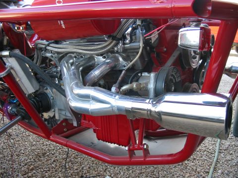 1993 Ford Taurus - The engine bay of a custom vehicle features polished exhaust headers and a red tubular frame.