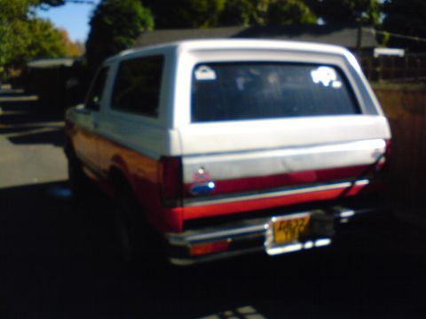 1989 Ford Bronco - This 1989 Ford Bronco features a distinctive red and white two-tone paint scheme and a rear-facing view.