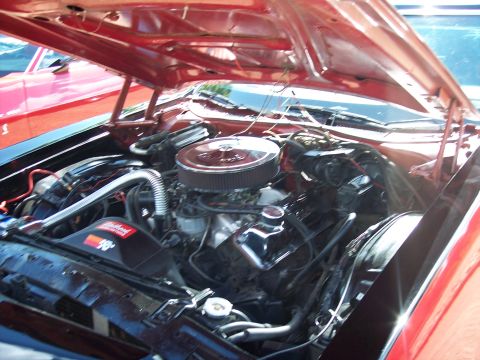1972 Ford Ranchero - The engine bay of a red vehicle is visible with the hood open, revealing the V8 engine and other components.