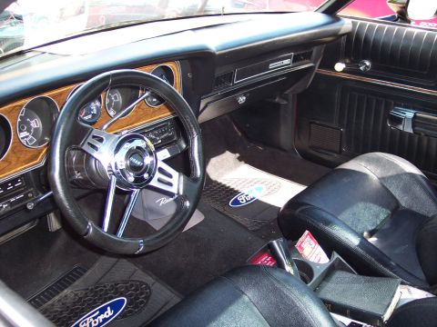 1972 Ford Ranchero - The interior of a 1972 Ford Ranchero features a Grant steering wheel, woodgrain dashboard accents, and Ford-branded floor mats.