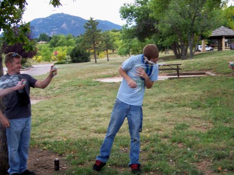 1972 Ford Ranchero - Two men engage in a silly string fight in a park setting, with a mountain range visible in the distance.