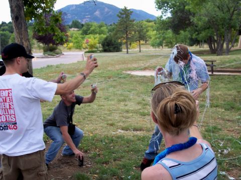 1972 Ford Ranchero - A group of people are having fun outdoors, spraying streamers at each other in a park-like setting with mountains in the background.
