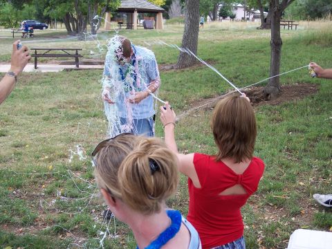1972 Ford Ranchero - A man is covered in streamers as others spray him with more in an outdoor park.