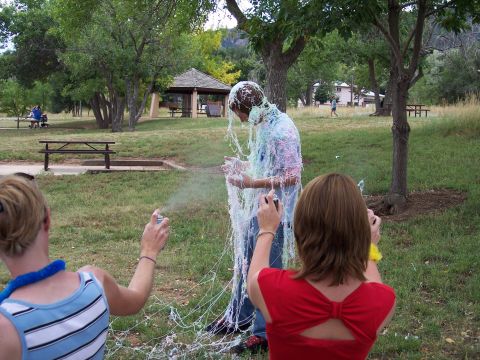 1972 Ford Ranchero - A person is covered in string as others spray it on them in a park setting.