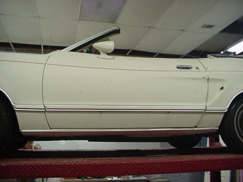 1977 Ford Mustang II - A white 1977 Ford Mustang II convertible is shown from the side while elevated on a lift.