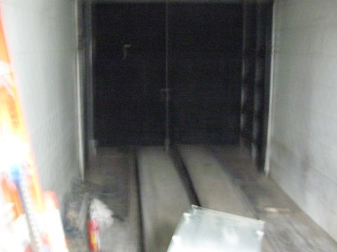 1990 Ford Bronco - dim, slightly blurred view inside an empty enclosed cargo trailer showing floor ramp rails and the rear doors.