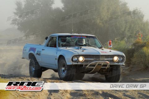 1984 Ford Bronco - This modified pickup truck competes in an off-road race, navigating a dusty course with visible sponsor decals.