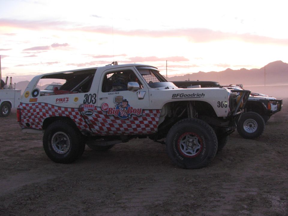 White and red checkered off-road race SUV number 303 with Big n Boy graphics on dirt