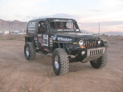 1990 Ford Bronco - black Jeep-bodied off-road race vehicle numbered 302 with ATK Engines and BFGoodrich graphics sits on a dusty desert lot.